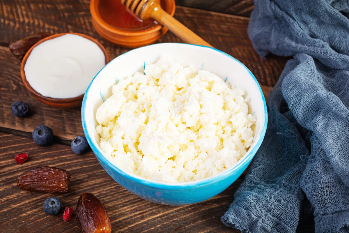 A bowl of creamy cottage cheese topped with fresh berries, sliced banana, and a sprinkle of nuts, surrounded by vibrant ingredients like cherry tomatoes, cucumbers, and avocado, showcasing a mix of sweet and savory options for pairing with cottage cheese.